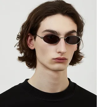Young person with medium-length brown hair wearing small oval dark sunglasses and a black shirt.